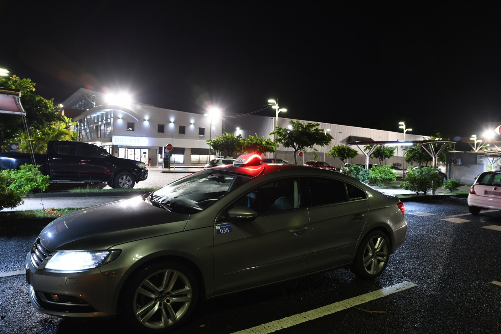 Le taxi gris TAXI LI photographié de trois quarts sur un parking de nuit